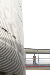 Obraz premium Supervisors walking on elevated walkway between factory buildings