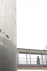 Fototapeta premium Supervisors walking on elevated walkway between factory buildings
