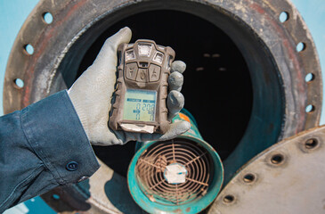 Worker hand holding gas detector inspection safety gas testing at front manhole tank