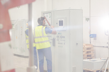 Engineers working at control panel in factory