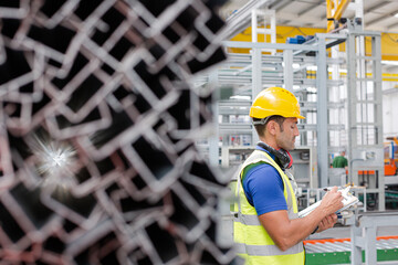 Factory worker with clipboard inspecting steel parts in factory