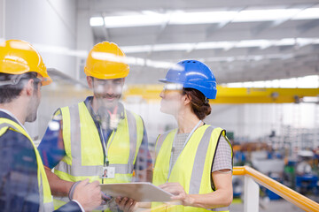 Supervisors and worker with clipboard talking in factory