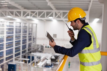 Obraz na płótnie Canvas Male supervisor with digital tablet talking, using walkie-talkie on platform in factory