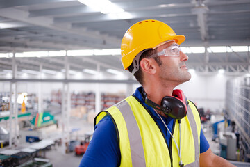 Portrait serious male worker in protective eyewear and hard-hat in factory