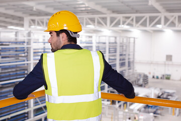 Serious male supervisor leaning on platform railing in factory