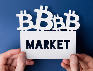 Hands holding a bitcoin cryptocurrency market sign