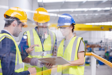 Supervisors and worker with clipboard talking in factory