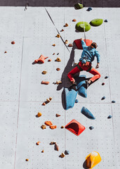 One Caucasian man professional rock climber workouts at training center in sunny day, outdoors. Concept of healthy lifestyle, tourism, nature, motion.