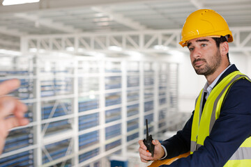 Male supervisor using walkie-talkie on platform in factory