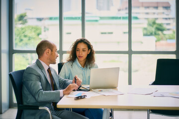 Businessman and woman are talking and discussing with laptop in meeting room
