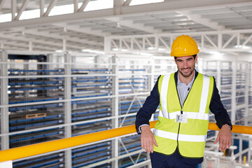 Serious male supervisor leaning on platform railing in factory