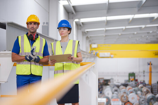Supervisor and workers with clipboard talking in factory