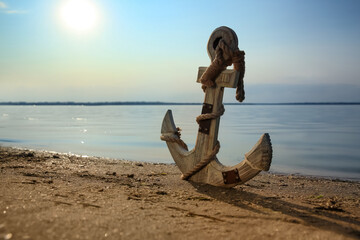 Wooden anchor on river shore near water