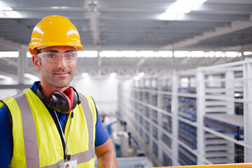Portrait serious male worker in protective eyewear and hard-hat in factory