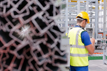 Factory worker with clipboard inspecting steel parts in factory