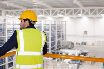 Serious male supervisor leaning on platform railing in factory