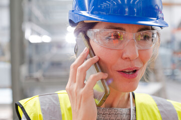 Close up female worker talking on smart phone in factory