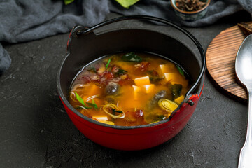 miso soup on cast iron bowl on dark stone table
