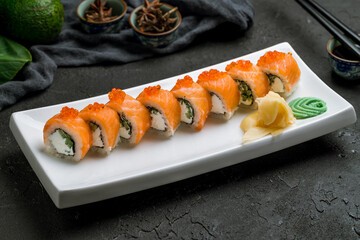 Philadelphia roll with salmon on white plate on dark stone table