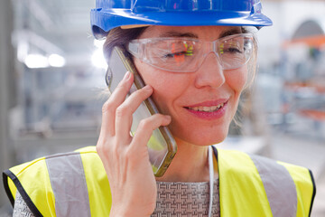 Close up female worker talking on smart phone in factory