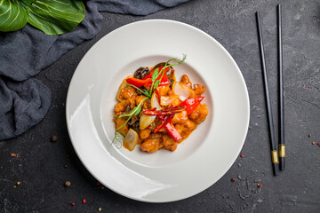 chicken in sweet and sour sauce , chinese cuisine on dark stone table top view