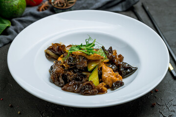 fried Meat with shiitake mushrooms on plate on dark stone table