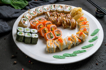 set of rolls and sushi on white plate on dark stone table