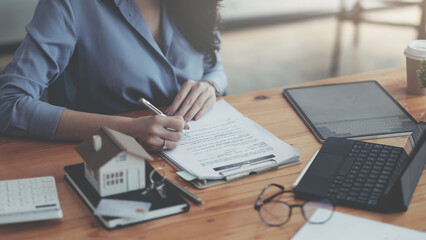 Close up real estate agent with house model hand putting signing contract, signing of modest...