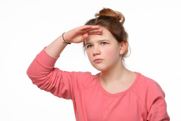 Portrait of a curious young girl looking far away with hand at her forehead, trying to see something far away
