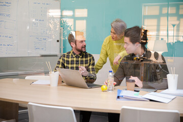 Obraz premium Three colleagues working at computer in conference room