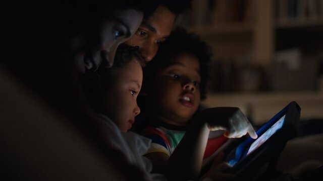 happy family using tablet computer with children mother and father watching movie with kids on touchscreen technology enjoying relaxing evening before bedtime 