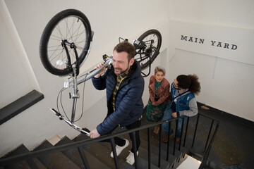 Friends carrying bicycle up stairwell