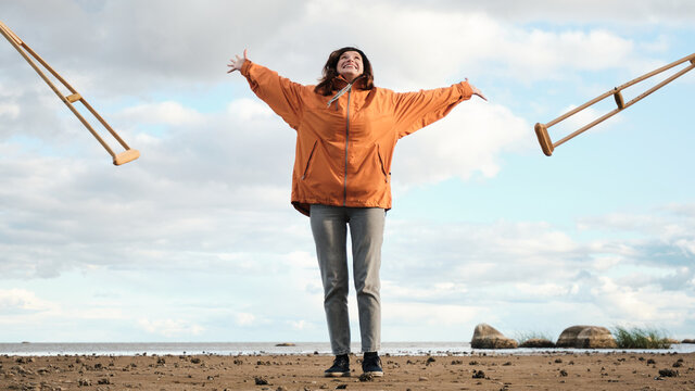 The woman throws away the crutches. The first steps after a broken leg. Rehabilitation after limb injury