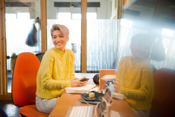 Obraz premium Portrait of young woman working at desk, smiling