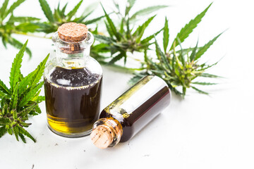 CBD oil in glass bottles and cannabis leaves at white table. Close up. Medicine and cosmetic product.
