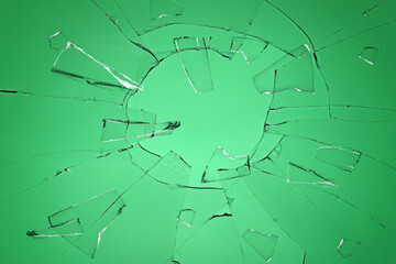 Broken glass with cracks on green background