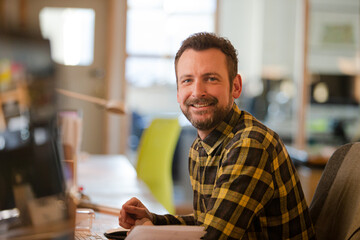 Obraz premium Portrait of young man posing in office, smiling