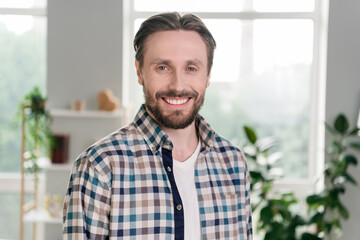 Portrait of attractive cheerful content guy wearing checked shirt staying home light white room...