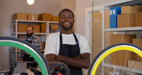Afro-american man repair bicycle in garage workshop smiling at camera