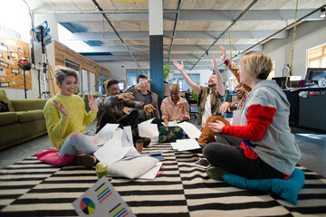 Fototapeta premium Team sitting on office floor, discussing paperwork