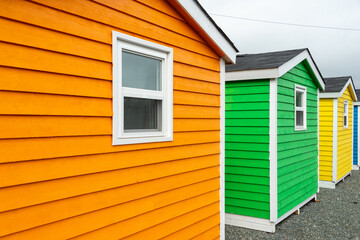 The exterior walls of bright orange,  yellow, green, and blue shed with narrow wooden horizontal...