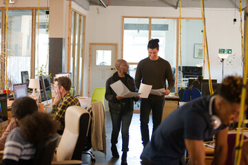 Two colleagues discussing paperwork in office
