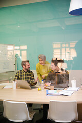 Three colleagues working at computer in conference room