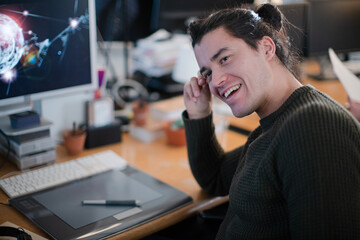 Smiling young man with long hair, working at computer