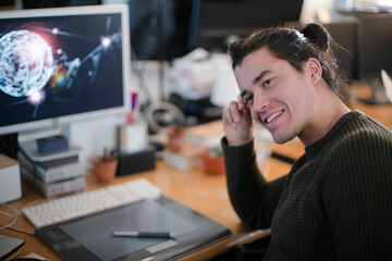 Smiling young man with long hair, working at computer