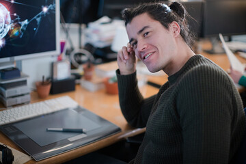 Smiling young man with long hair, working at computer