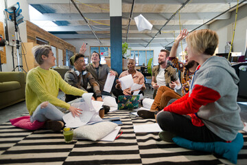 Obraz na płótnie Canvas Team sitting on office floor, discussing paperwork
