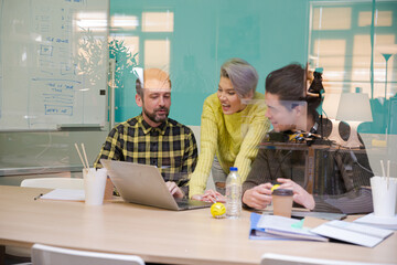 Obraz premium Three colleagues working at computer in conference room