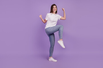 Photo of delighted girl raise fists win isolated over purple background