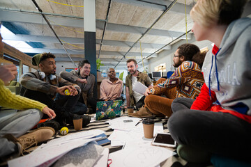 Team sitting on office floor, discussing paperwork